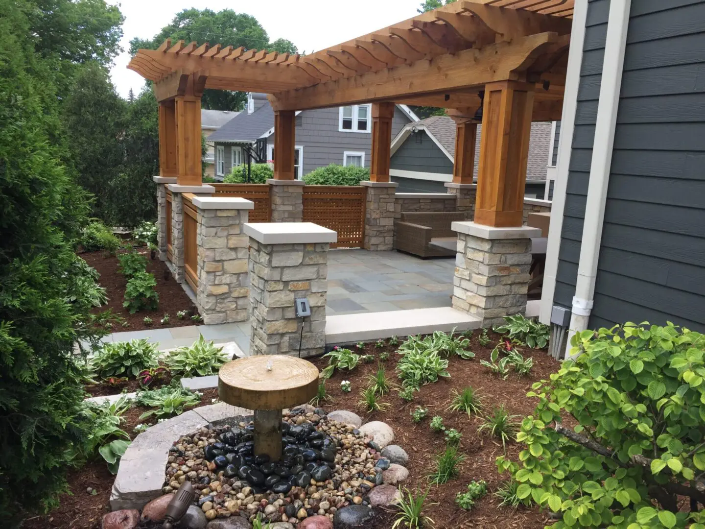 Custom patio with fountain, natural stone pillars and wood pergola installation in Oak Brook, IL