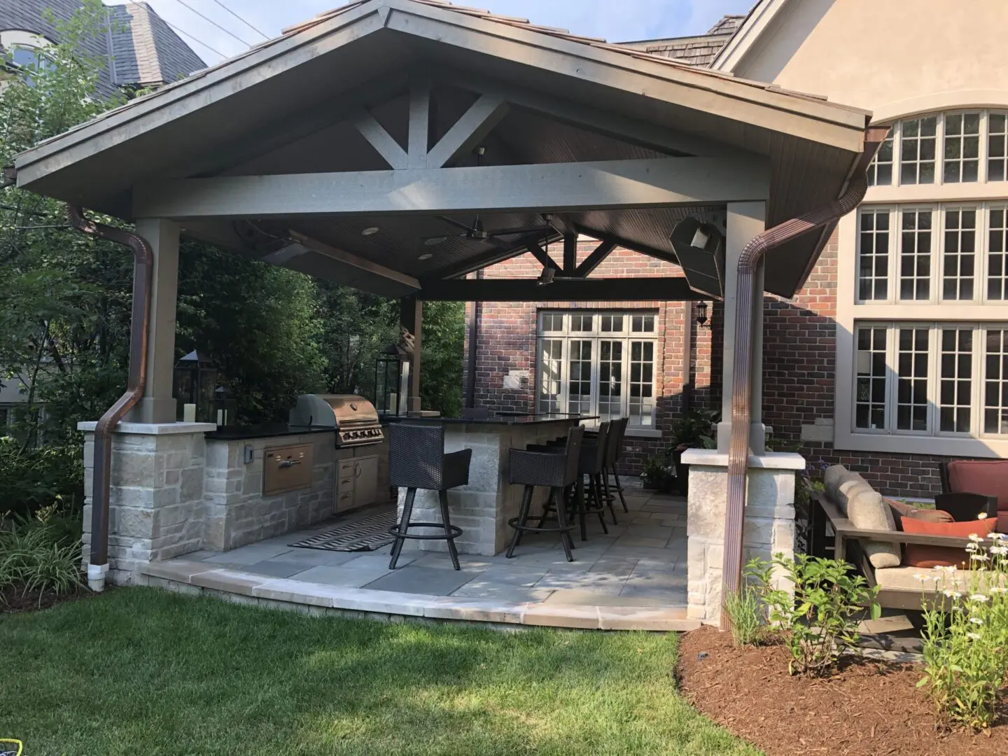 Stone outdoor kitchen island with grill, cabinets, and bar seating in Hinsdale, IL