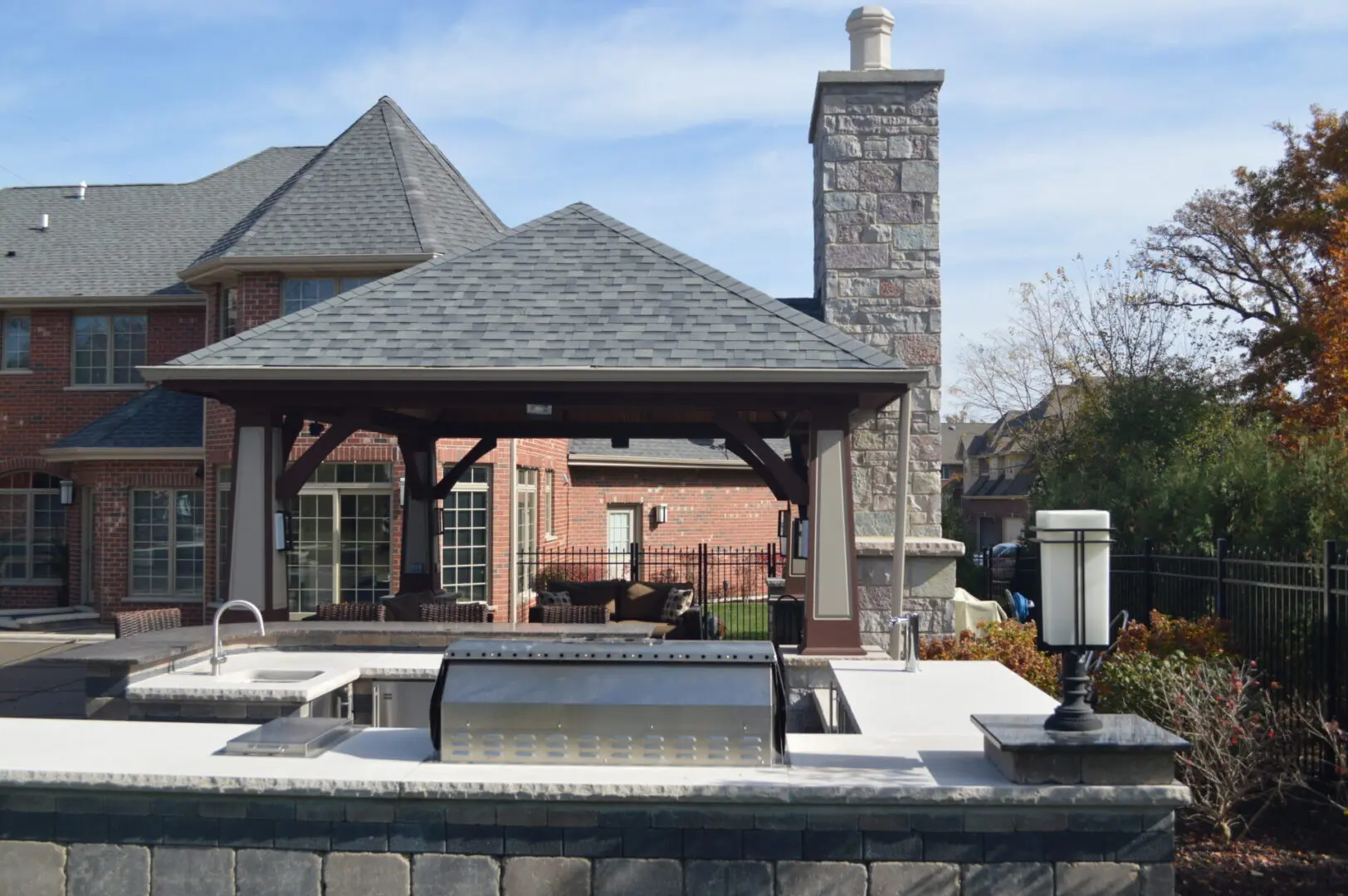 Custom outdoor kitchen with paver patio, pergola style pavilion, and fireplace installation in Lemont, IL
