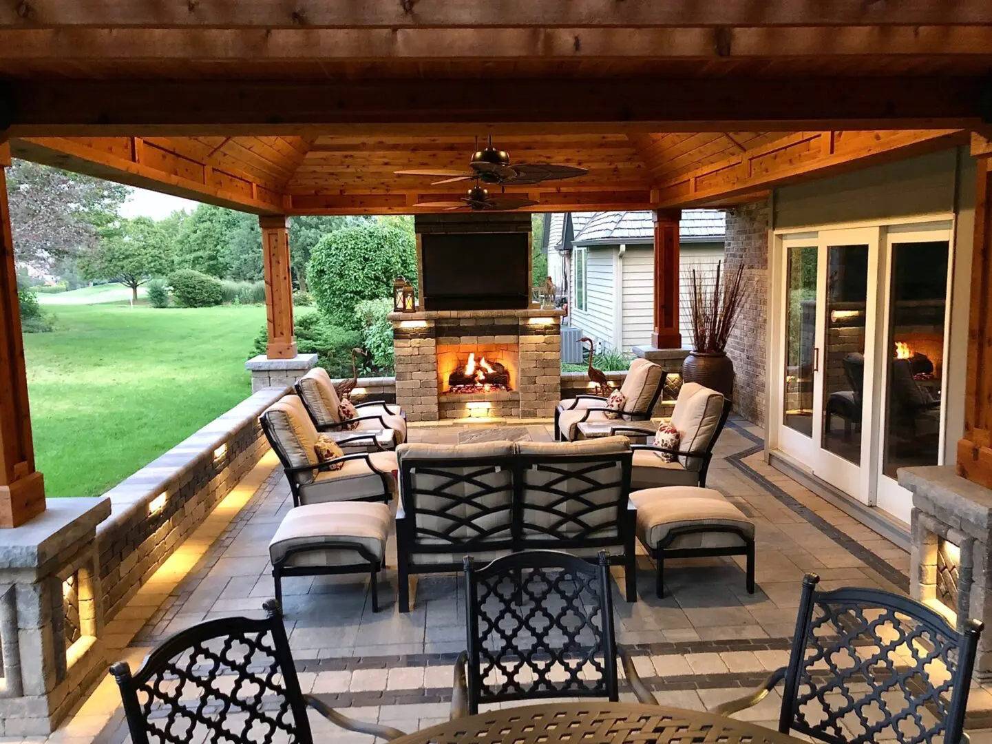 Outdoor pavilion with pergola-style design, seating area, fireplace, fan, and landscape lighting in Naperville, IL