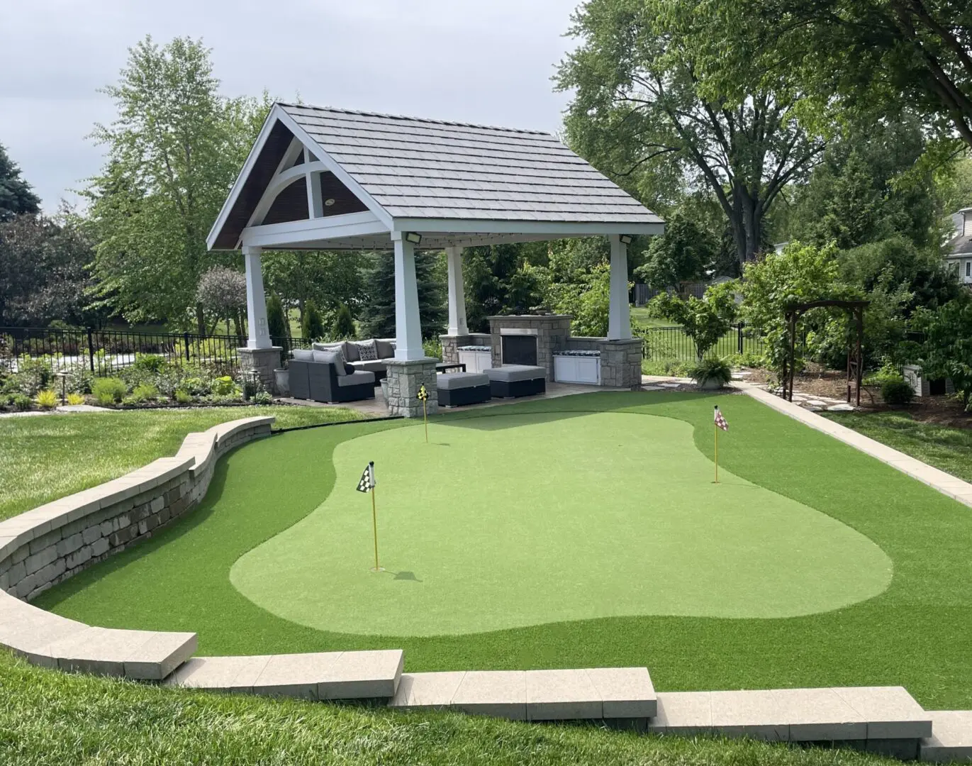 Outdoor living space with roof structure, fireplace, seating walls and putting green in Hinsdale, IL