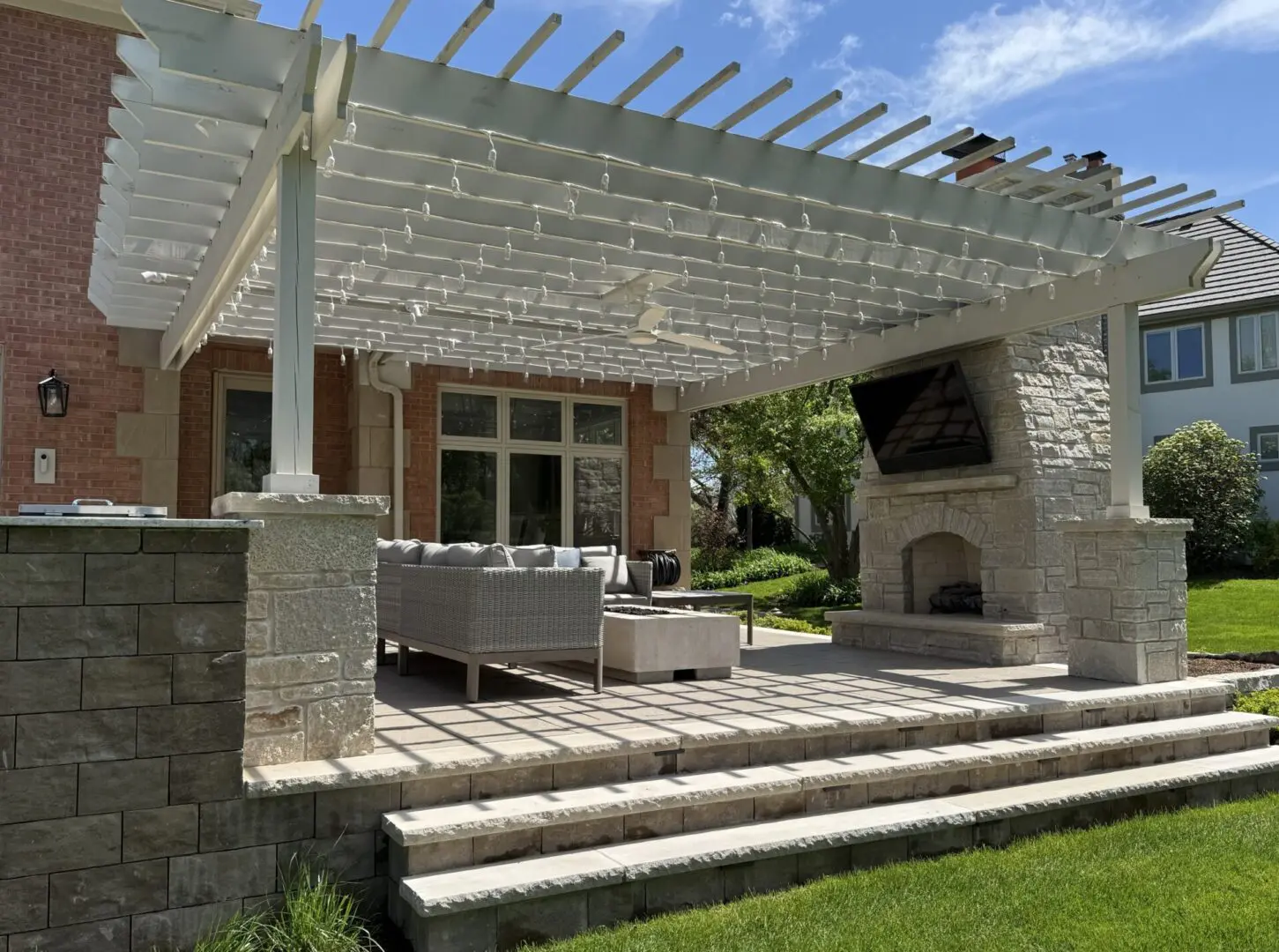 Custom pergola installed over natural stone pillars, natural stone fireplace, and paver patio in Oak Brook, IL