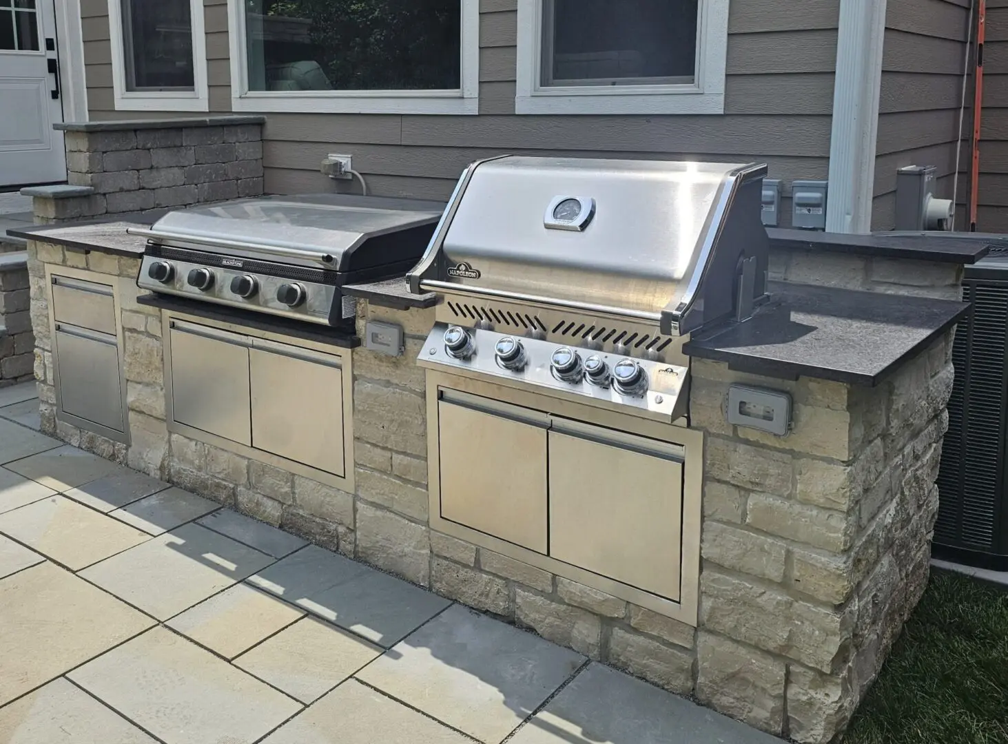 Custom outdoor kitchen with built in stainless steel grill, cabinets, and griddle in Western Springs, IL